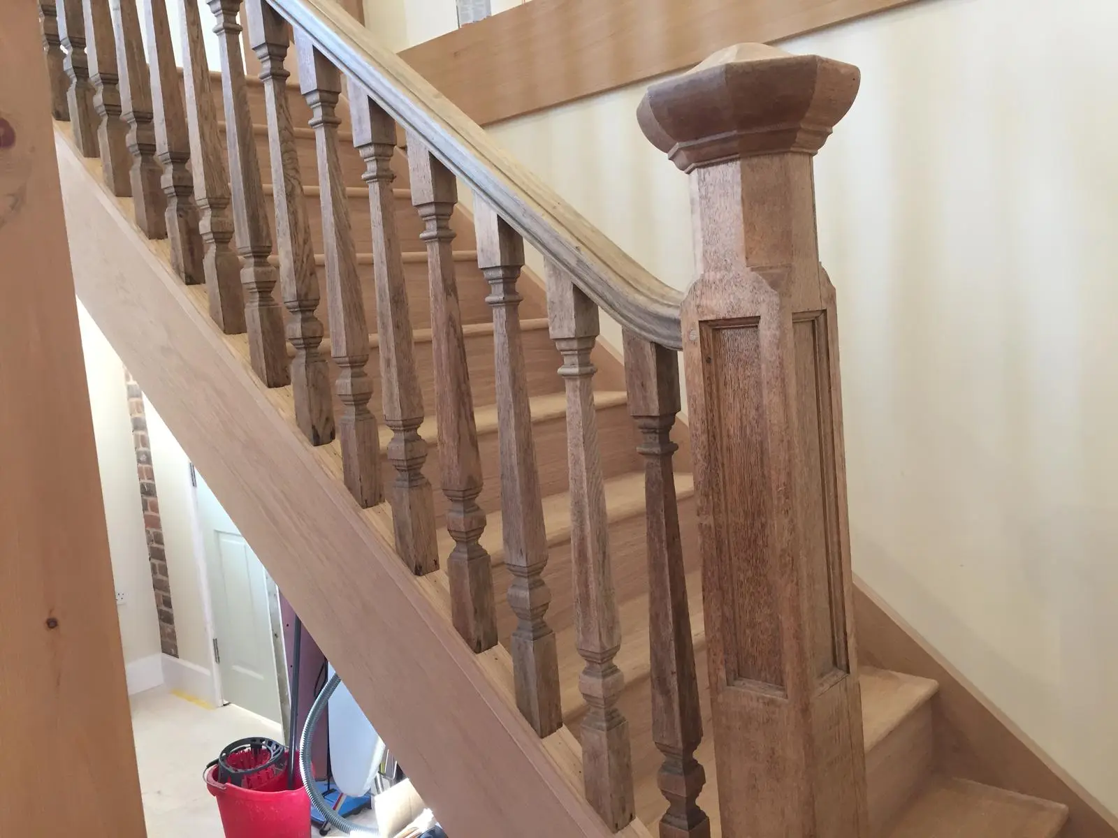 Close view of turned oak spindles and a panelled oak newel post with a moulded cap