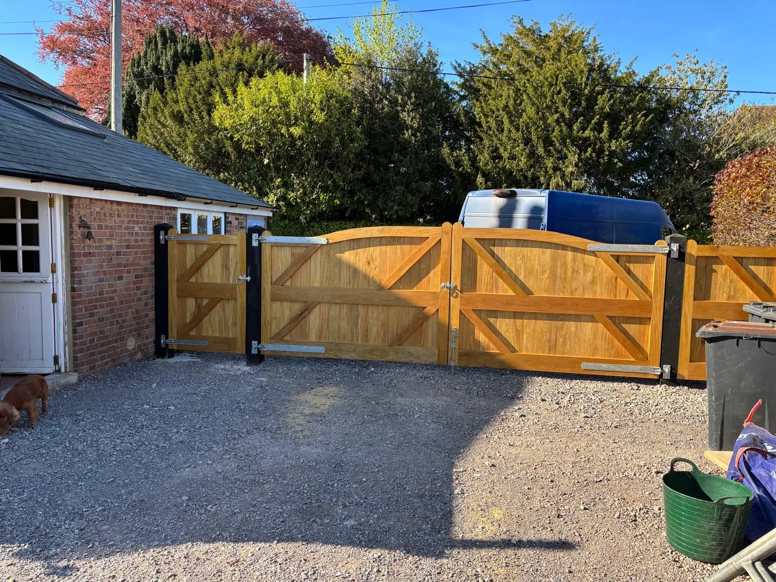 Framed and braced oak driveway gates with a matching pedestrian gate beside a brick garage