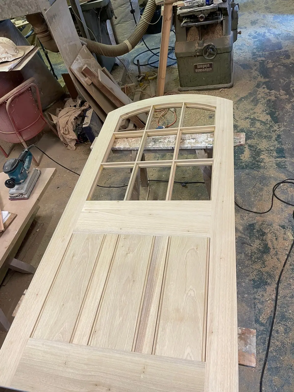 Bespoke arched timber door with glazed top lights and tongue-and-groove panelling, in build